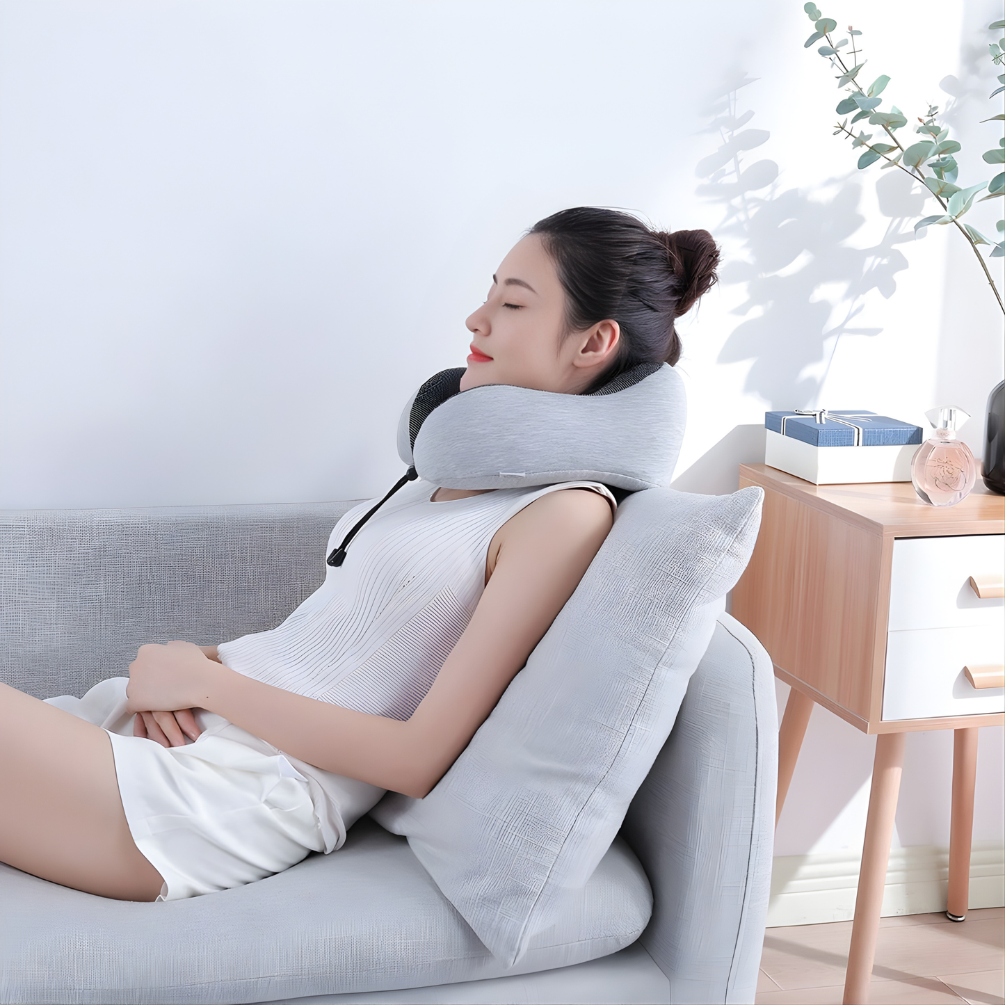 Adjustable memory foam travel neck pillow worn by woman 
relaxing on sofa at home for neck support and comfort